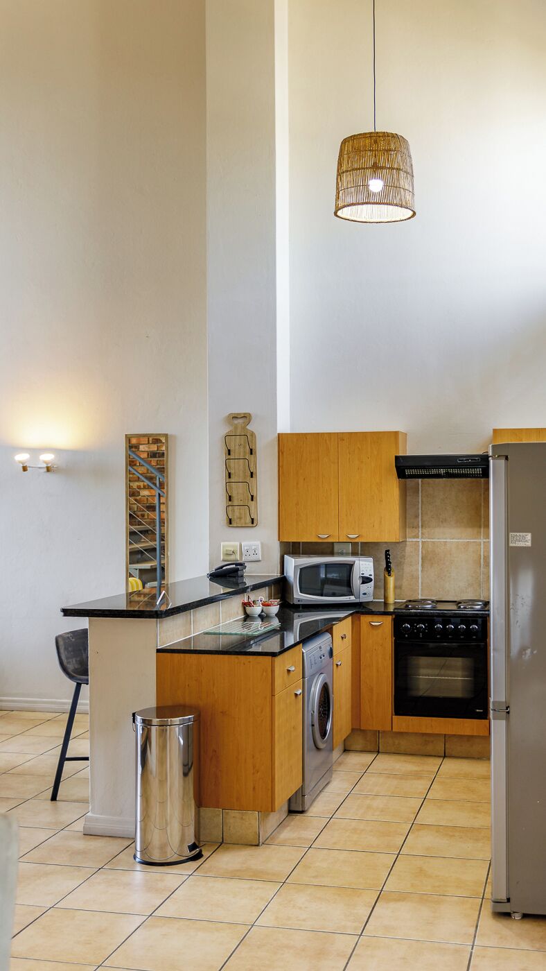 Uma cozinha moderna com ilha central, eletrodomésticos de aço inoxidável e luminária pendente.