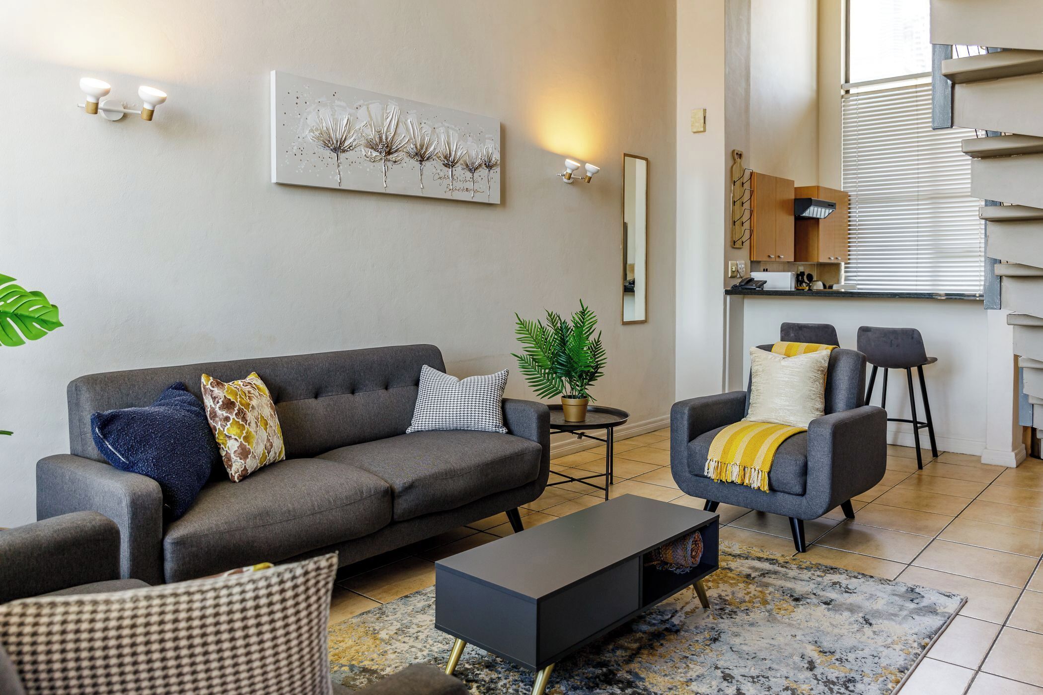 A modern living room with a grey sofa, a coffee table, and a potted plant.