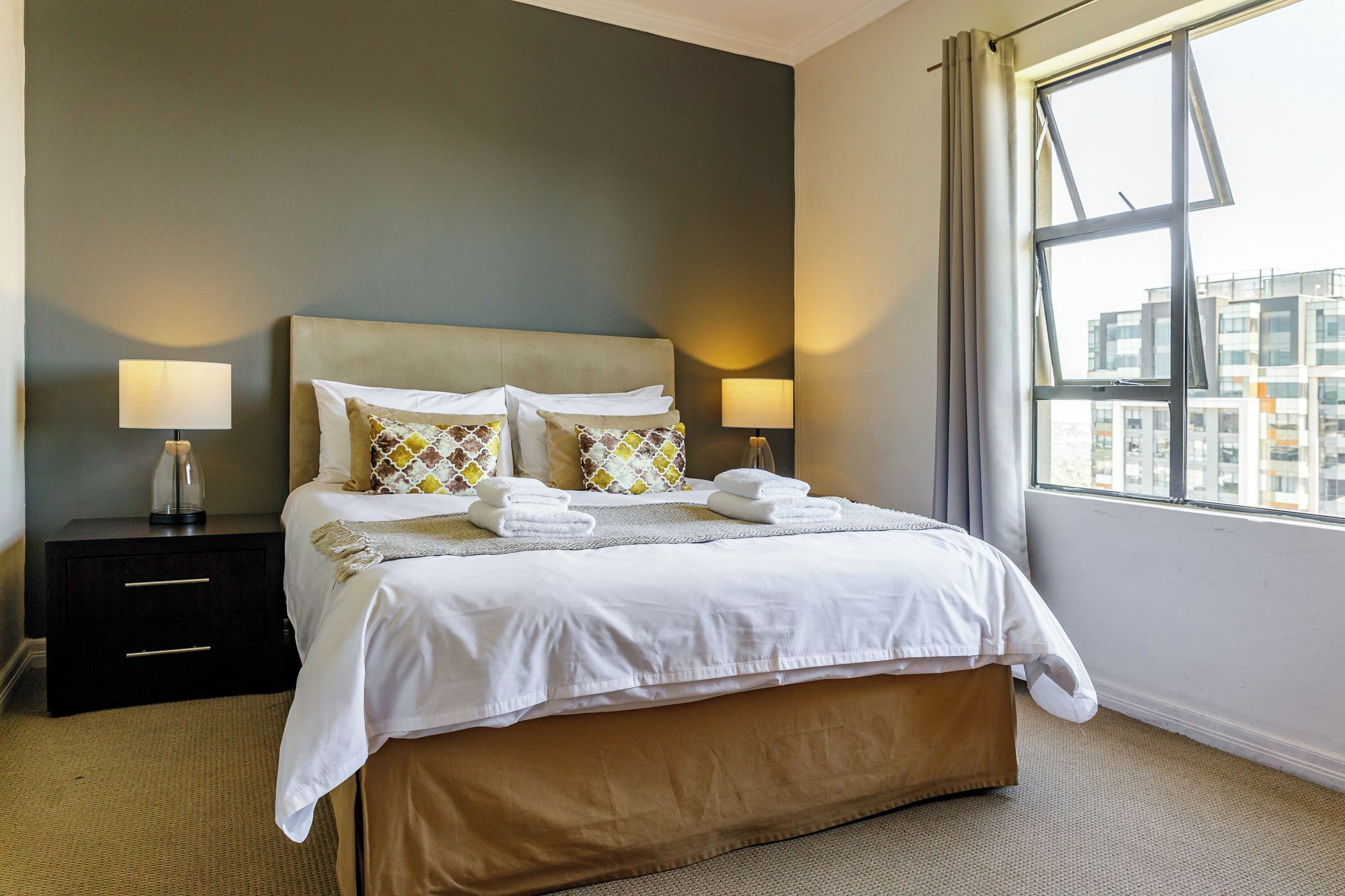 A hotel room with a bed, two bedside tables, and a window with curtains.