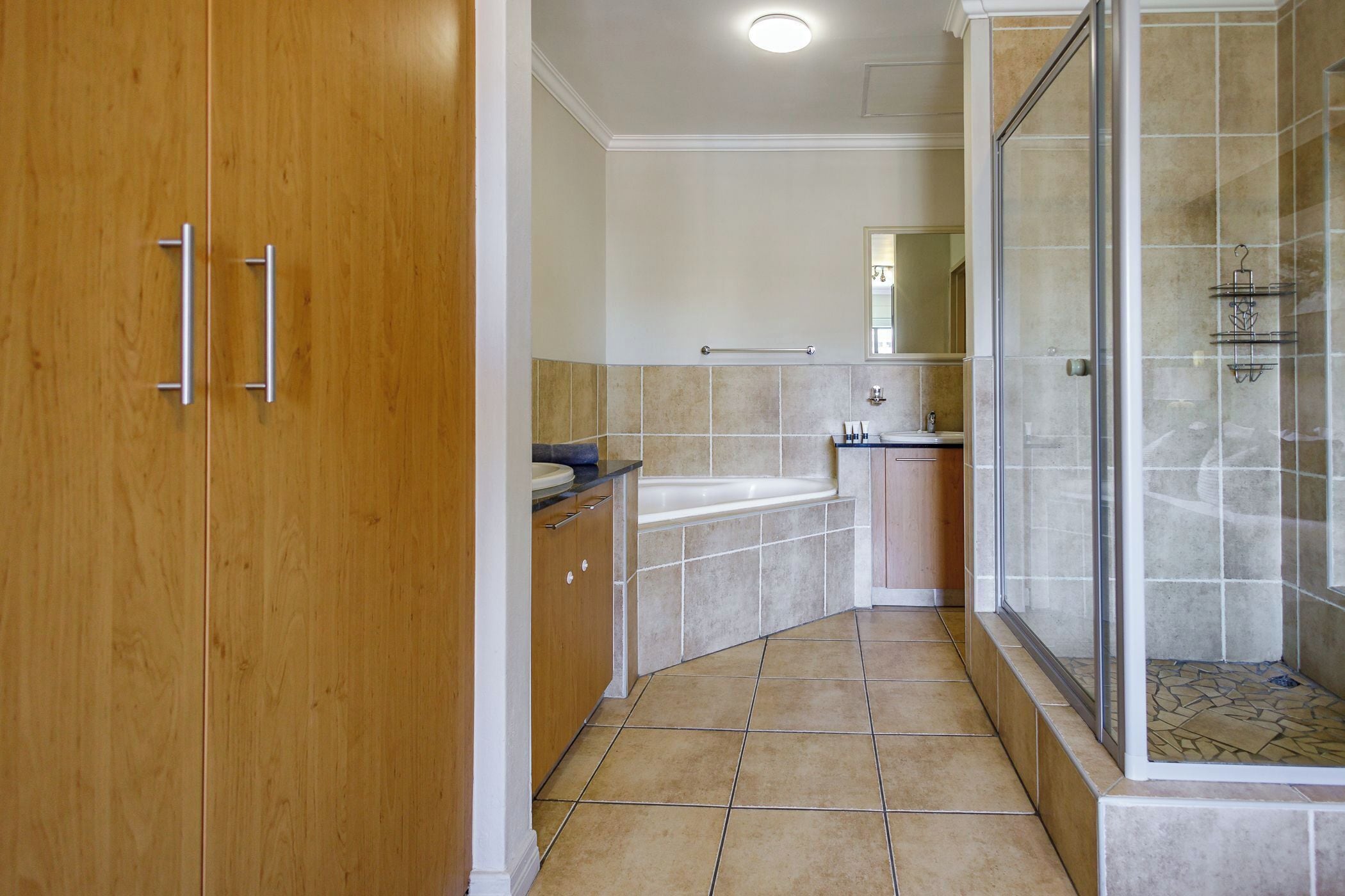 Une salle de bain avec une porte en bois, une baignoire, un espace douche et un sol carrelé.