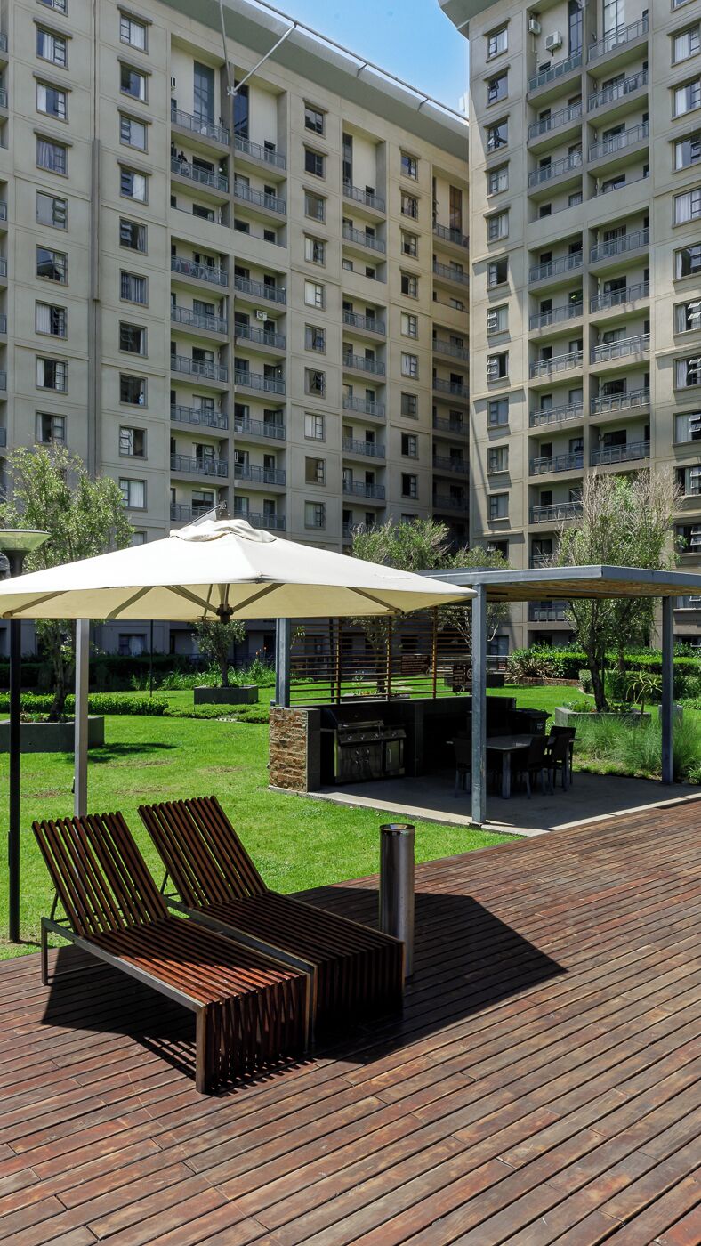 A rooftop terrace with a wooden deck, lounge chairs, and a covered seating area.