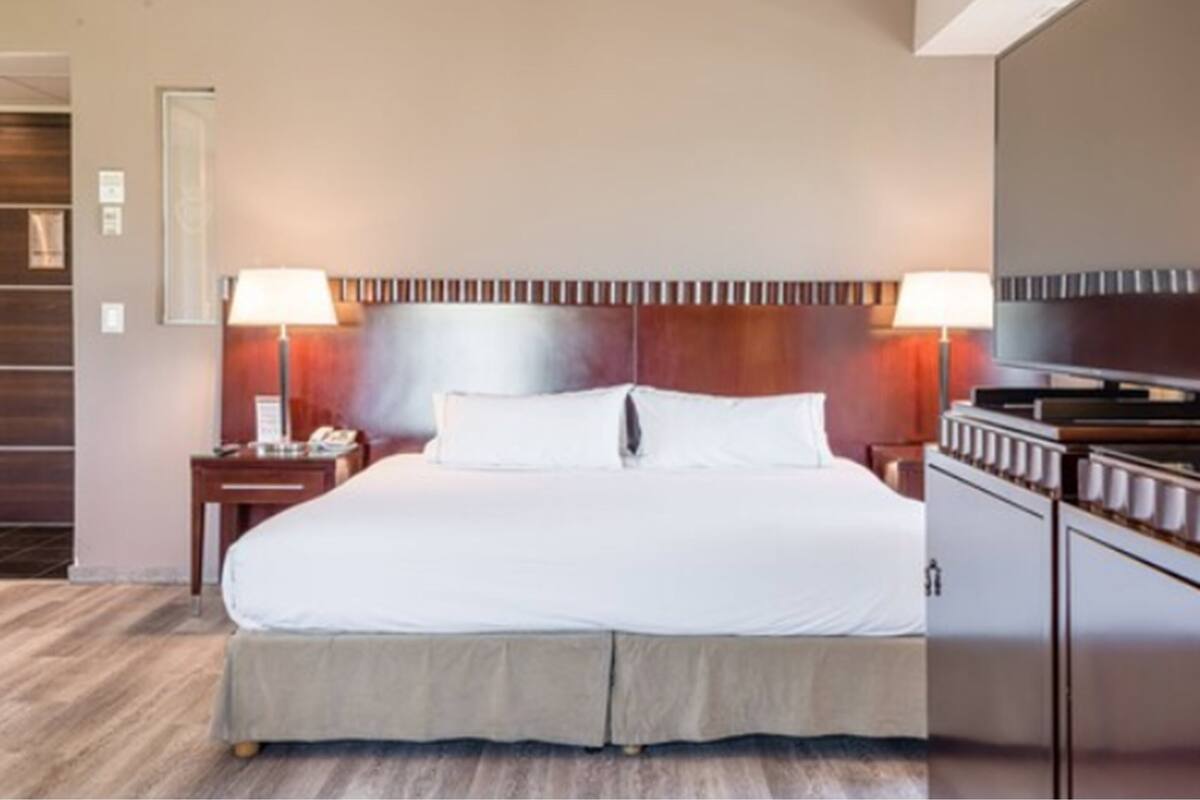 A hotel room with a large bed, two bedside tables, and a built-in TV.