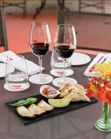 A table set with wine glasses, plates, and food including flatbreads and a small bowl of chutney.
