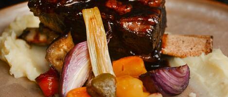 A plate of food with a piece of meat, vegetables, and mashed potatoes.