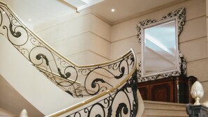 A marble staircase with ornate black metal railings and a decorative mirror at the top. - Diplomatic Hotel (Mendoza)