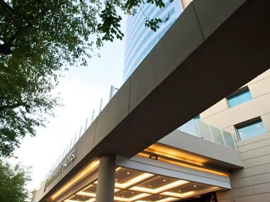 A modern hotel entrance with a covered walkway, large columns, and a glass facade.