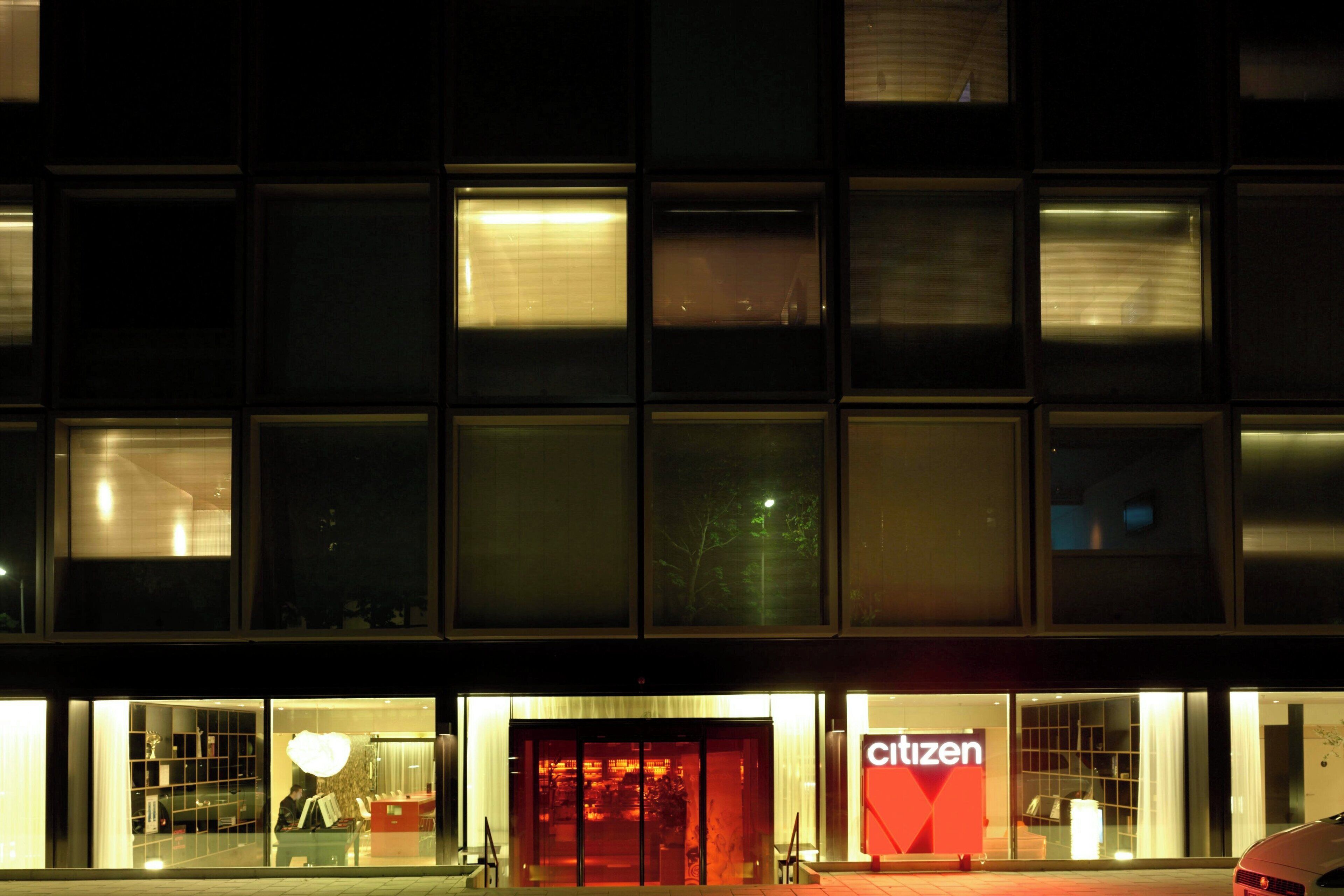 Un bâtiment doté de nombreuses fenêtres illuminées et d’une enseigne bien visible portant le mot « Citizen ».