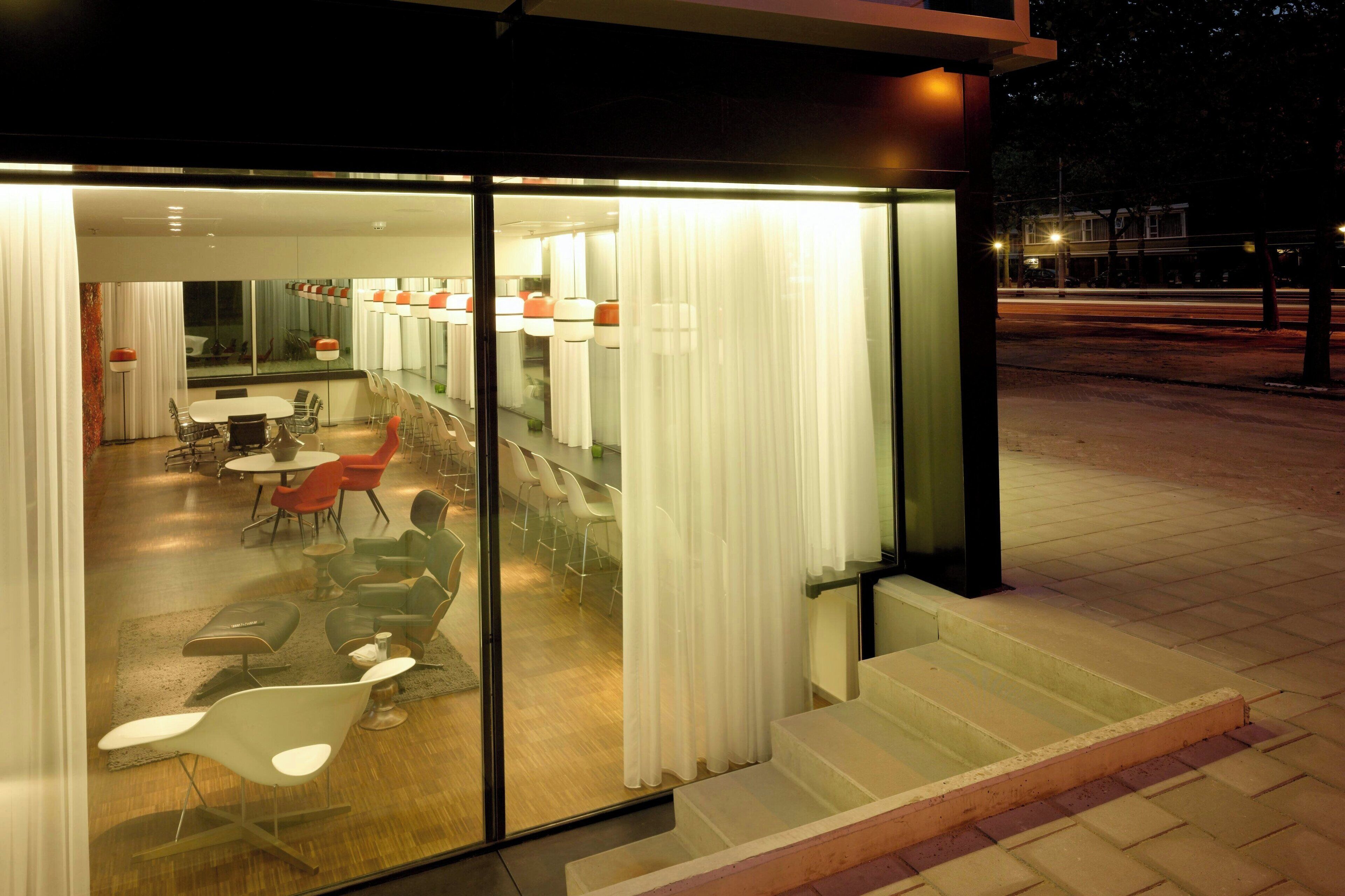 A modern hotel interior with a dining area, a kitchen, and a bar.