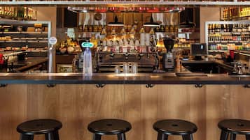 Eine Bar mit Hockern, einer Theke und Regalen voller Flaschen.