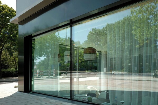 A modern building with large glass windows reflecting a street scene. - citizenM Amsterdam South (Amsterdam)