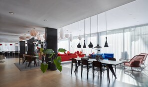 A spacious, modern dining area with a long table, multiple chairs, and pendant lighting. - citizenM Amsterdam South (Amsterdam)