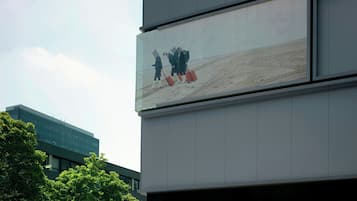 A modern building with a large billboard displaying a scene of people walking with luggage.
