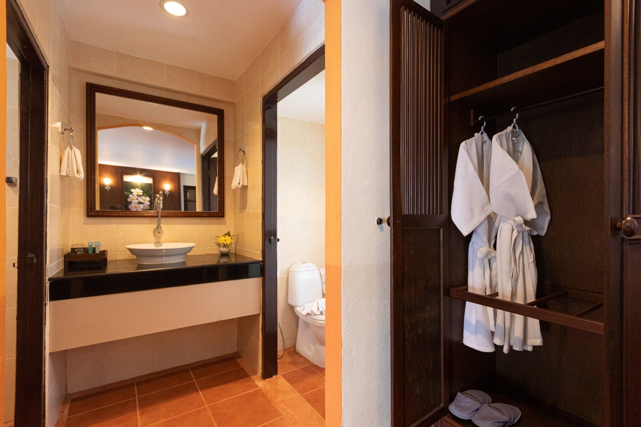 A bathroom with a sink, mirror, and a robe rack with towels.