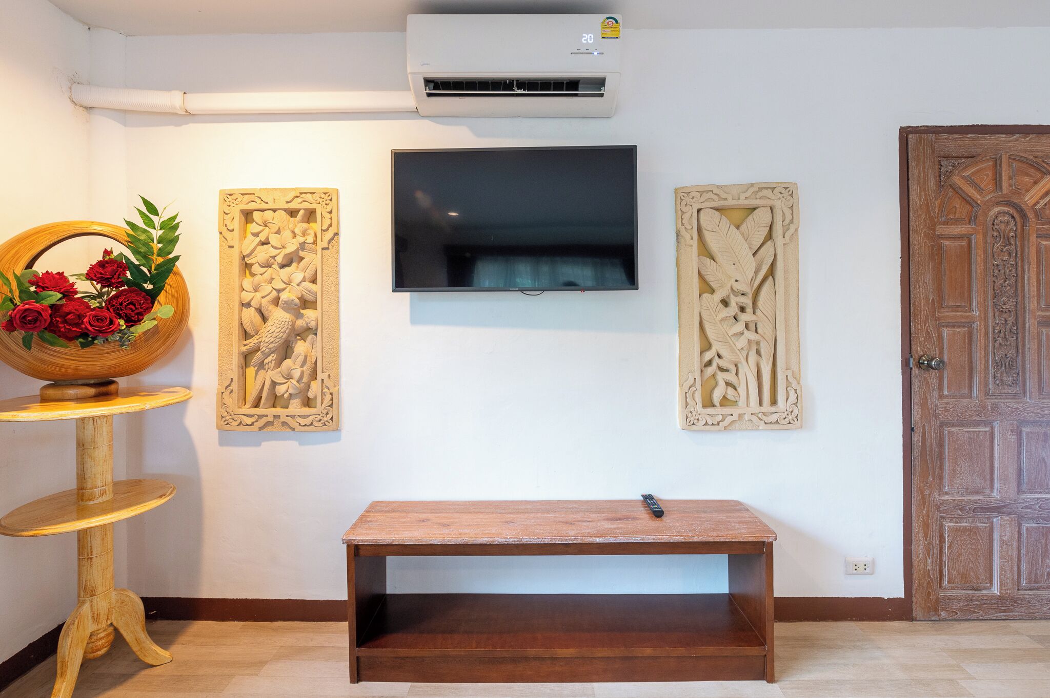 A room with a mounted TV, wooden bench, and two wall-mounted decorative panels.