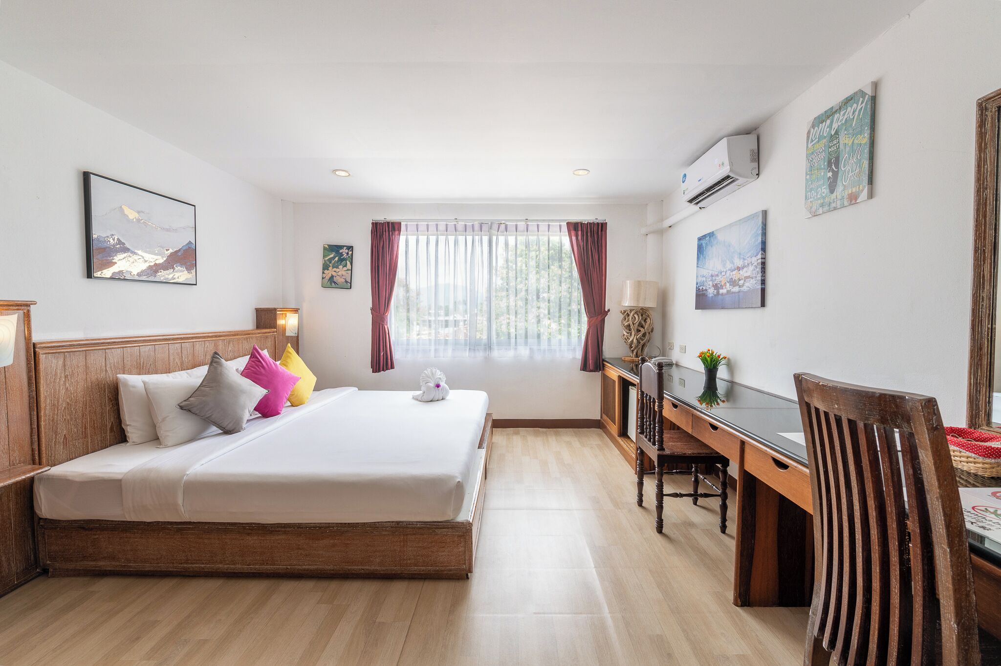 A hotel room with a bed, desk, chair, and artwork on the walls.