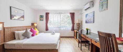A hotel room with a bed, desk, chair, and artwork on the walls.