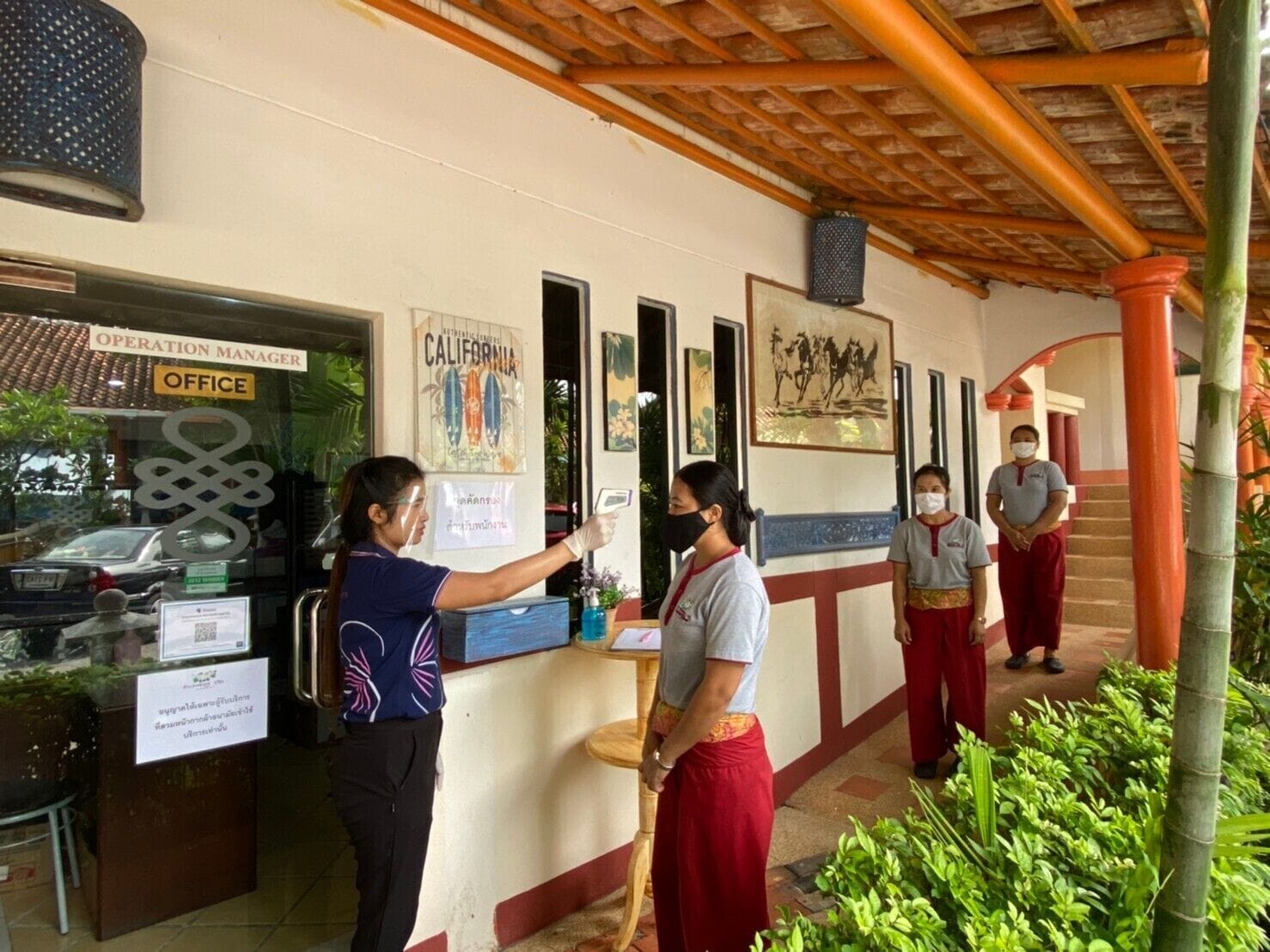 An office area with a reception desk, a sign reading "Operation Manager Office", and a person using a QR code scanner.