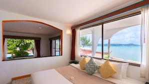 Habitación de hotel con una cama grande, vistas al mar y un balcón con piscina.