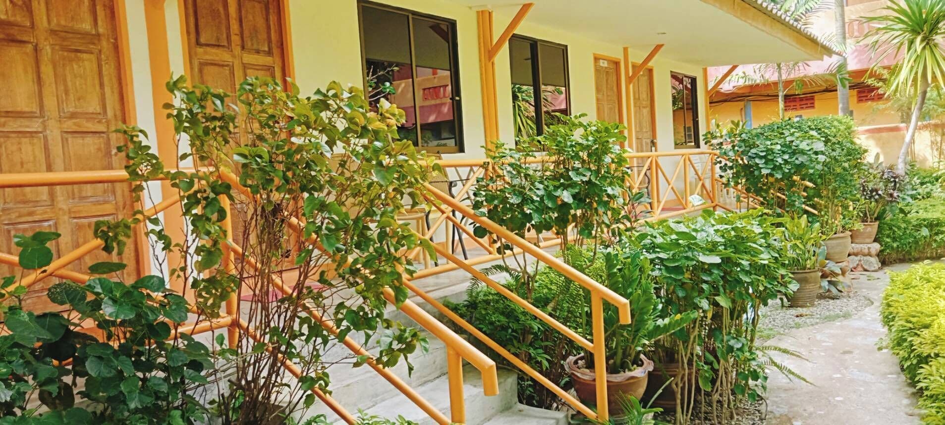 Una escalera con barandillas de madera rodeada de exuberante follaje y plantas en macetas.