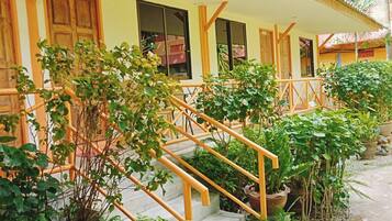 Una escalera con barandillas de madera rodeada de exuberante follaje y plantas en macetas.