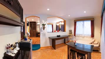 Habitación de hotel con comedor, cama con vistas, una mesita con un florero y un espejo.