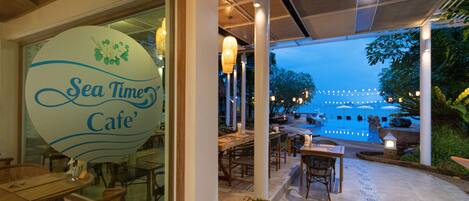 A restaurant with a sign reading "Sea Time Cafe" and outdoor seating with a pool view.