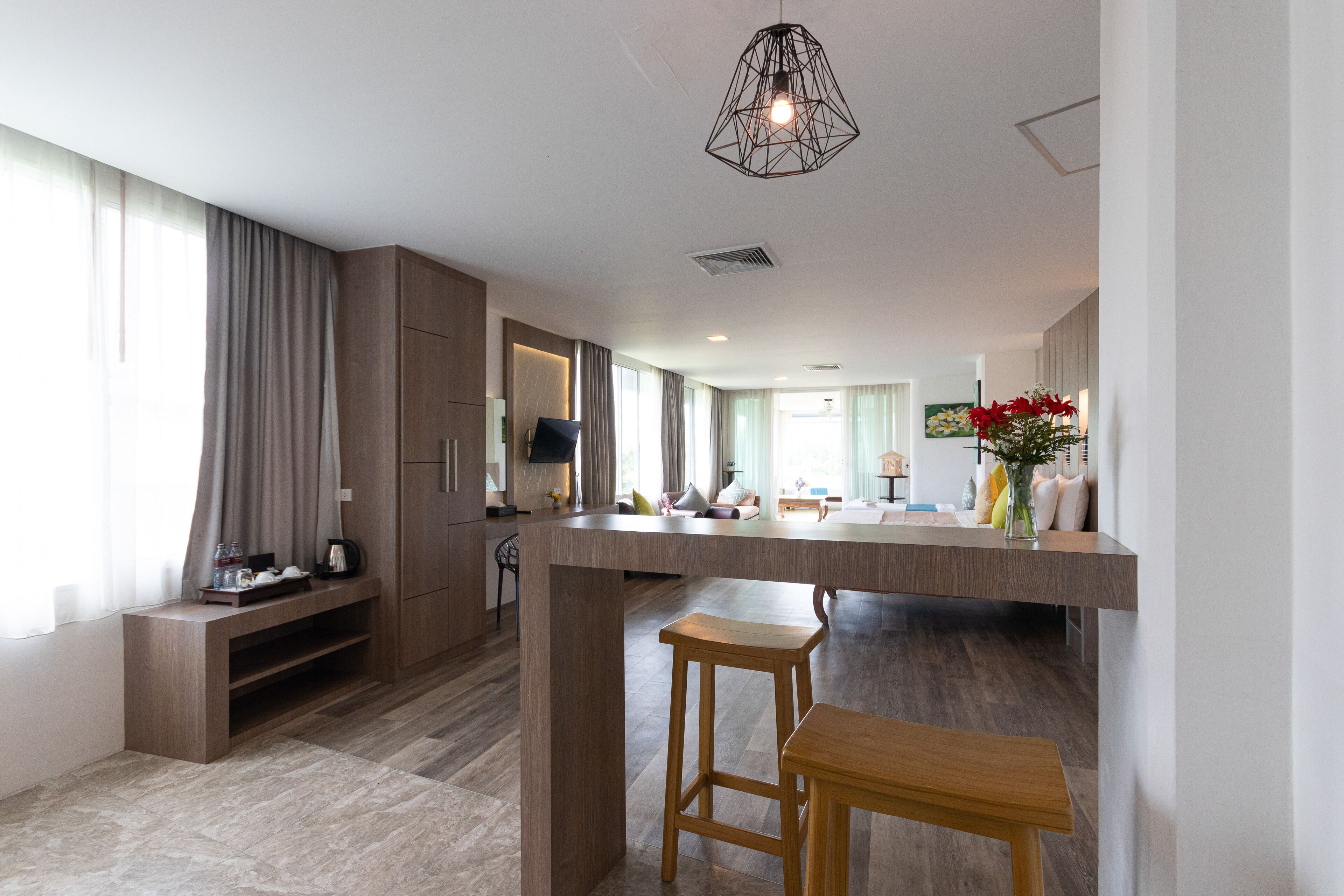 Una cocina moderna con una isla central, taburetes de madera y una lámpara colgante.