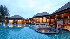 A large outdoor swimming pool with a hot tub, surrounded by lounge areas and covered seating.