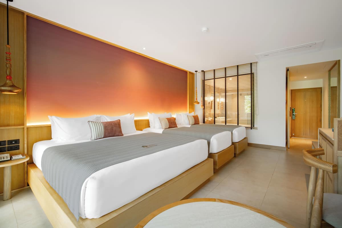 A hotel room with a large bed, bedside tables, a wooden headboard, and a view of the outside.