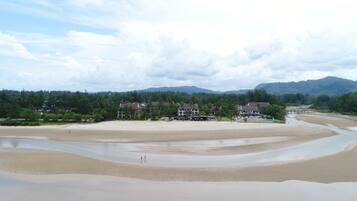 Un resort en la playa con varias edificaciones, una playa de arena y un río.