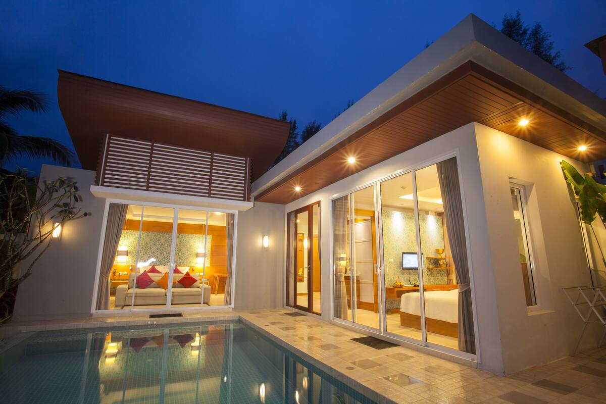 A modern house with a swimming pool, large sliding glass doors, and a balcony.