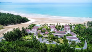 Un resort con varias edificaciones, una playa y una zona boscosa.