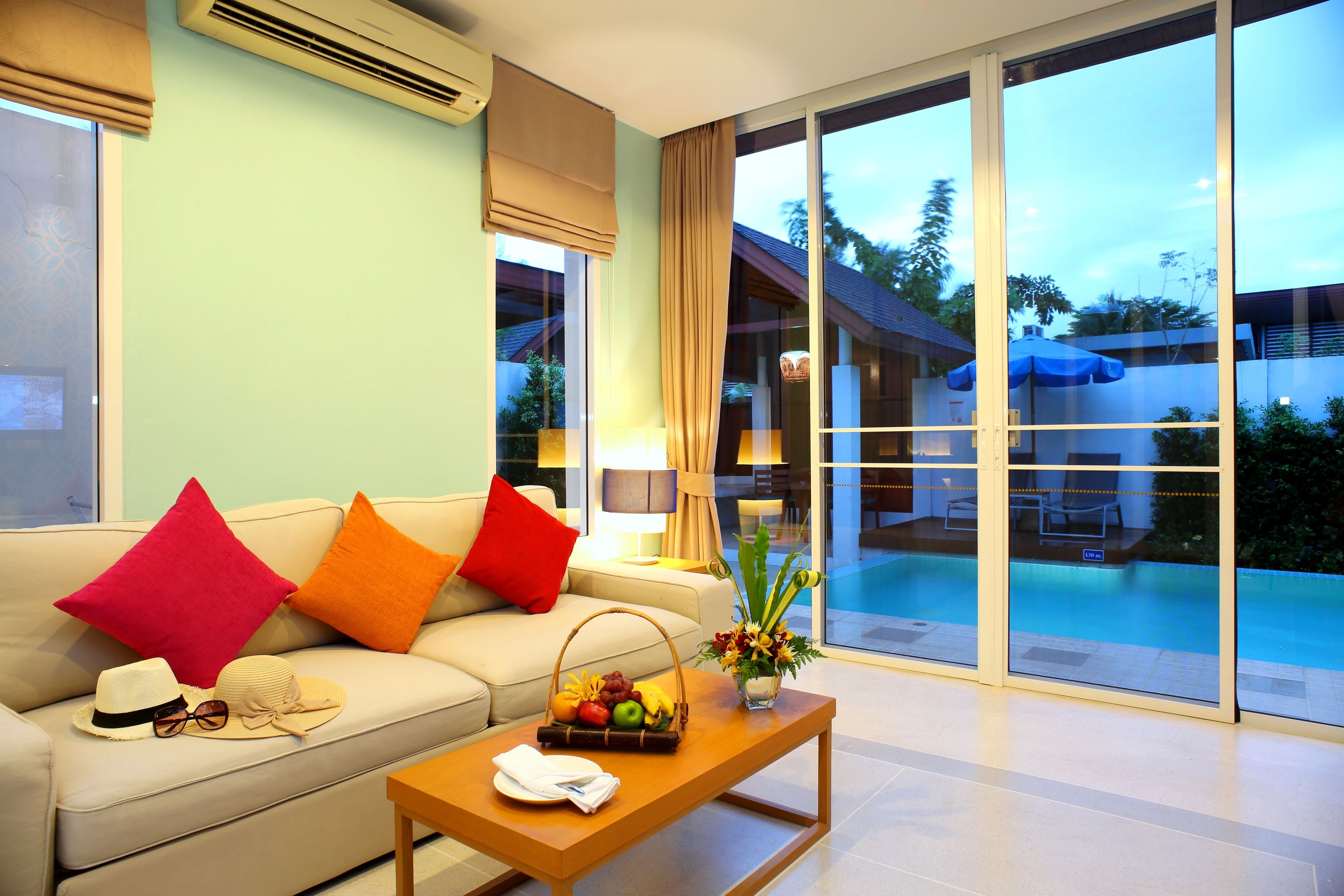 A modern living room with a sofa, a coffee table, and a view of an outdoor pool area.