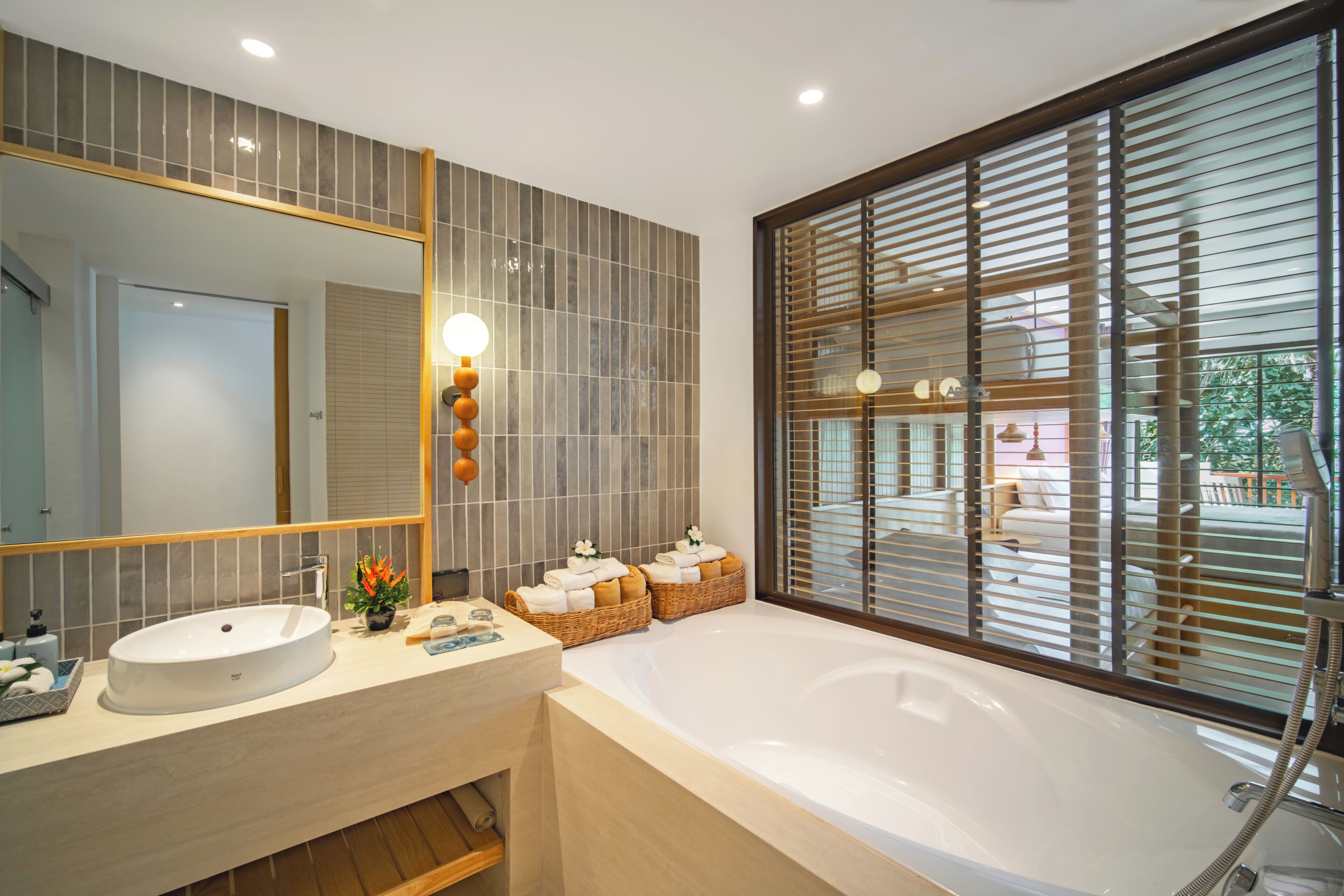 Une salle de bain moderne avec une grande baignoire, un lavabo rond et un grand miroir.