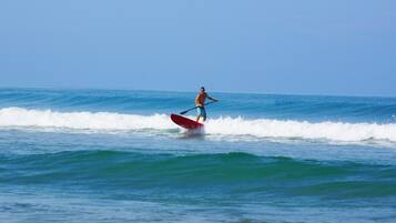 Una persona haciendo paddleboard sobre un mar tranquilo con olas.