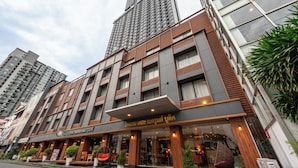 A modern hotel with a prominent entrance, large windows, and a sign in a foreign language. - The Bedrooms Boutique Hotel (Bangkok)