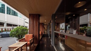 A modern interior with wooden paneling, a seating area with tables and chairs, and a view of the street outside. - The Bedrooms Boutique Hotel (Bangkok)