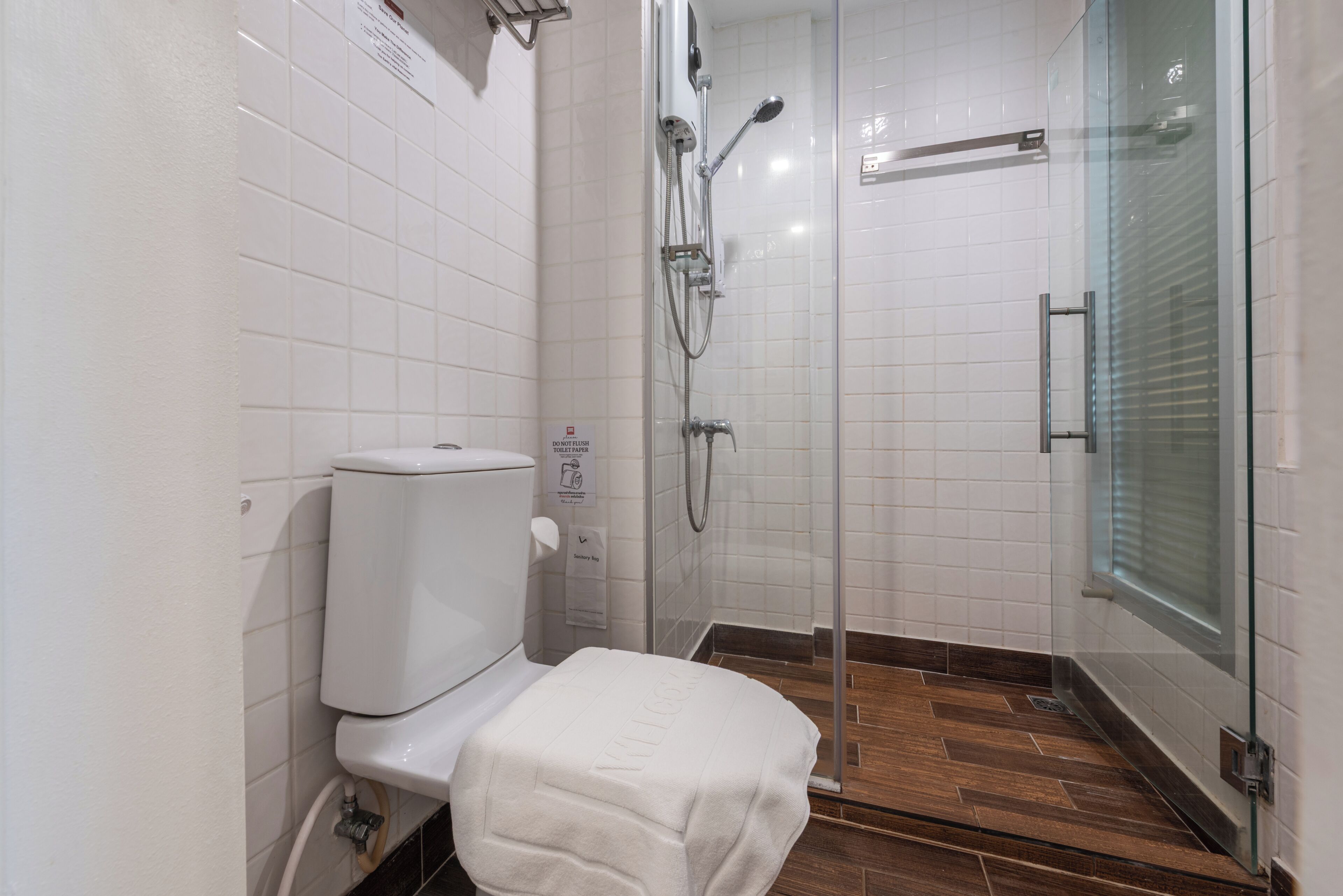 A modern bathroom with a toilet, shower, and glass-enclosed shower stall.