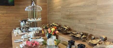 Montaje de bufé con diferentes alimentos, una exposición de frutas y un tostador.