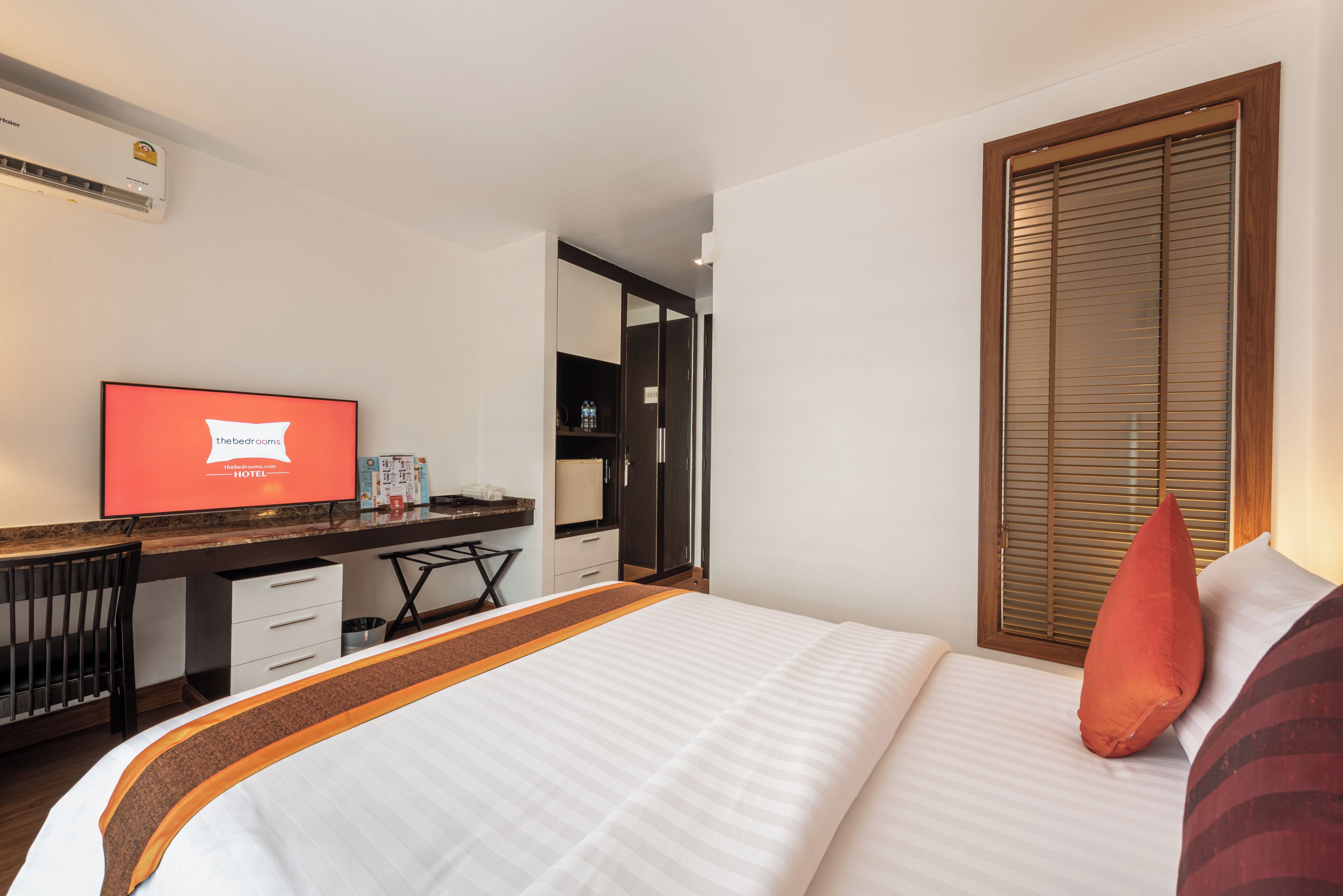 A hotel room with a bed, a television, a desk, and a wardrobe.