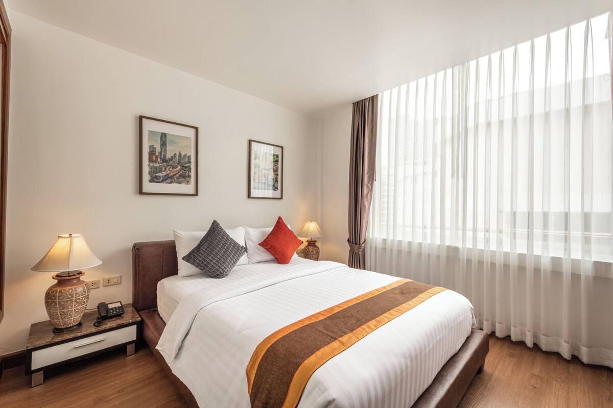 A hotel room with a bed, nightstand, lamps, and two framed pictures on the wall.