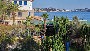 A coastal building with a white facade, blue shutters, and a tiled roof. - Hotel Petit Cala Fornells (Calvia)