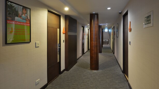 Un pasillo de hotel con puertas, un pilar grande y un cartel en la pared.