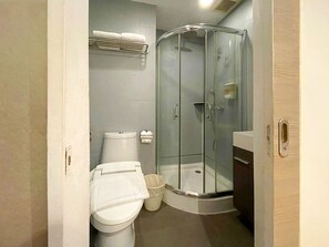 A bathroom with a toilet, a glass-enclosed shower, a towel rack, and a trash bin. - Arawana Express Phromphong (Bangkok)