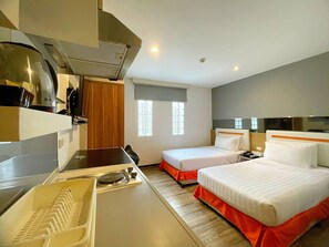 A hotel room with a kitchenette, two beds, a window, and a shower area. - Arawana Express Phromphong (Bangkok)