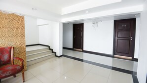 A hotel lobby with a staircase, a red chair, and two dark wooden doors. - Pattaya Hiso Hotel (Pattaya)