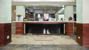 A reception area with a marble floor, wooden paneling, a clock, and a vase with flowers. - Pattaya Hiso Hotel (Pattaya)