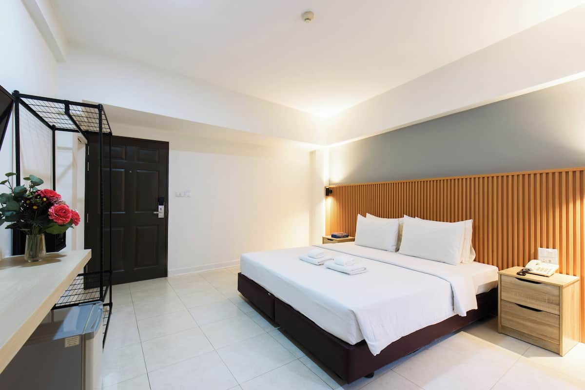 A modern hotel room with a bed, bedside table, and a desk with a chair.