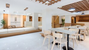 Un moderno vestíbulo de hotel con mostrador de recepción, zona de estar y mesas de comedor.