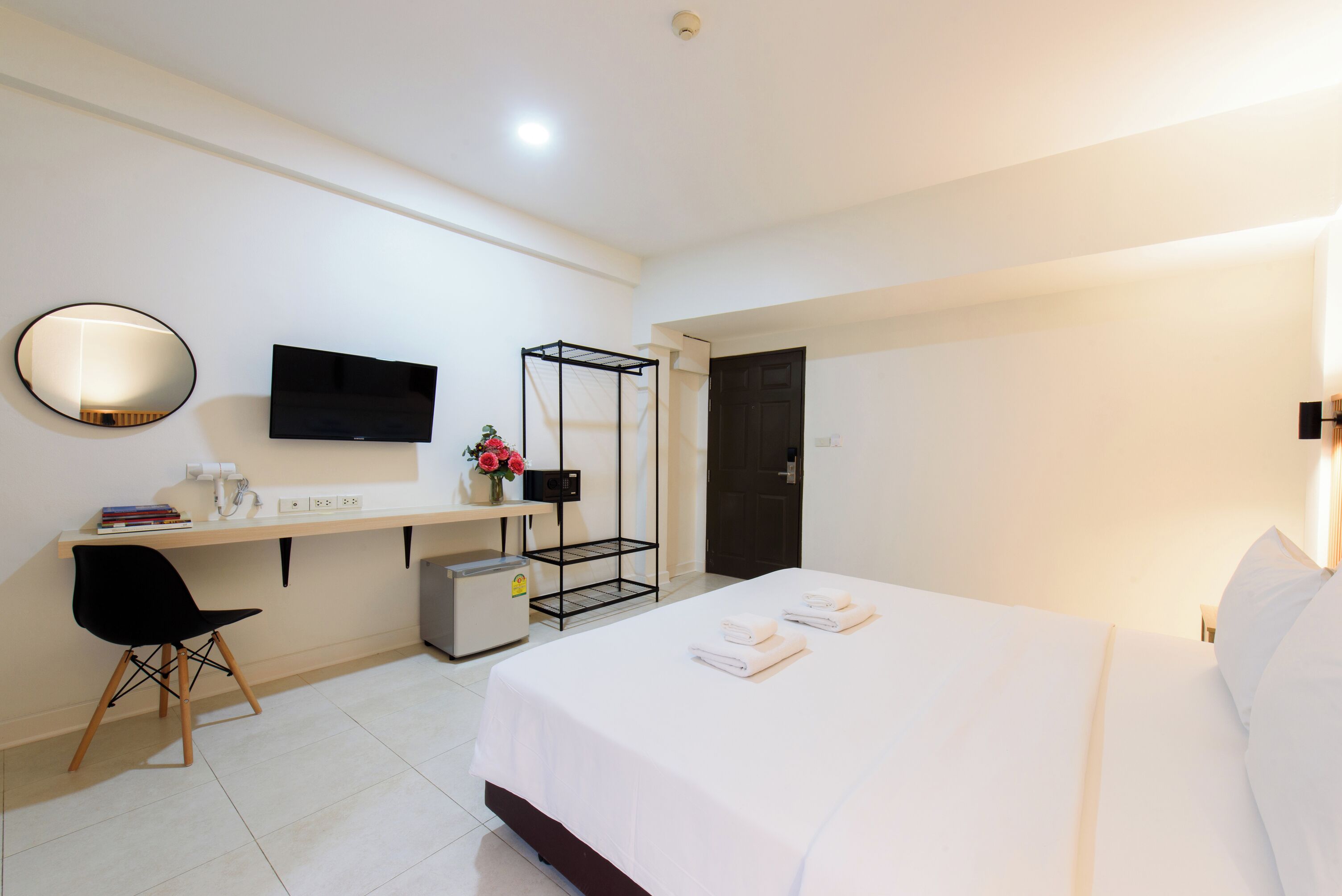 A hotel room with a bed, a desk with a chair, a TV, and a wardrobe.
